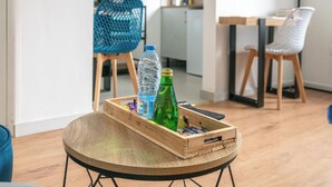 Un vassoio di legno con una bottiglia d'acqua, una bottiglia verde e una barretta di cioccolato su un tavolo rotondo.