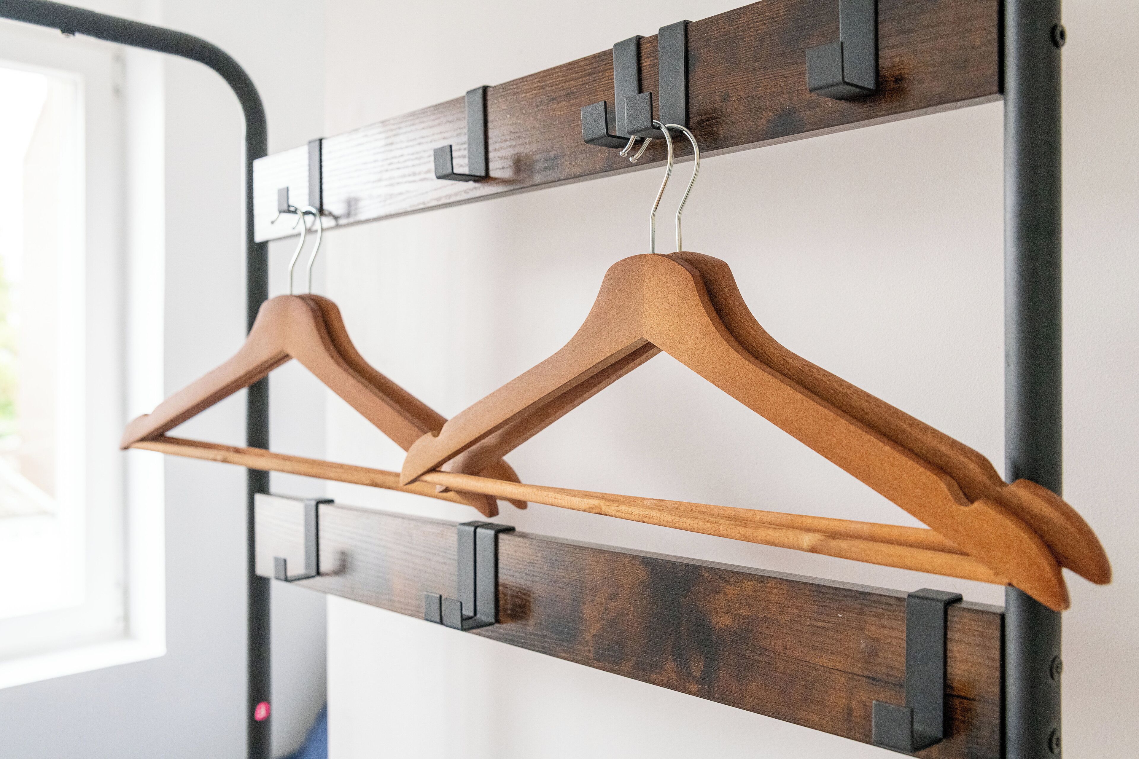 A wall-mounted wooden rack with two wooden hangers.