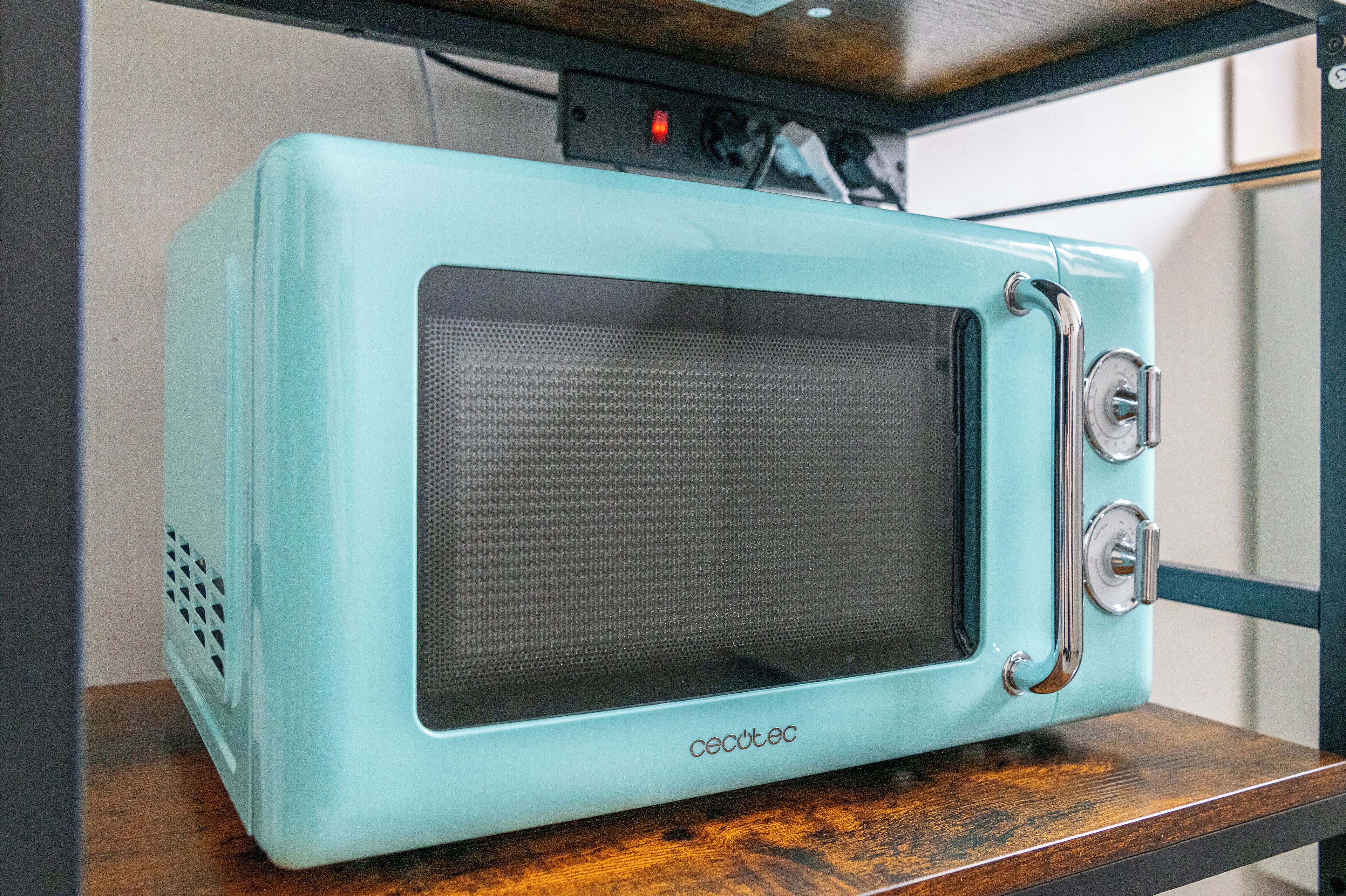 A teal vintage television on a wooden shelf.