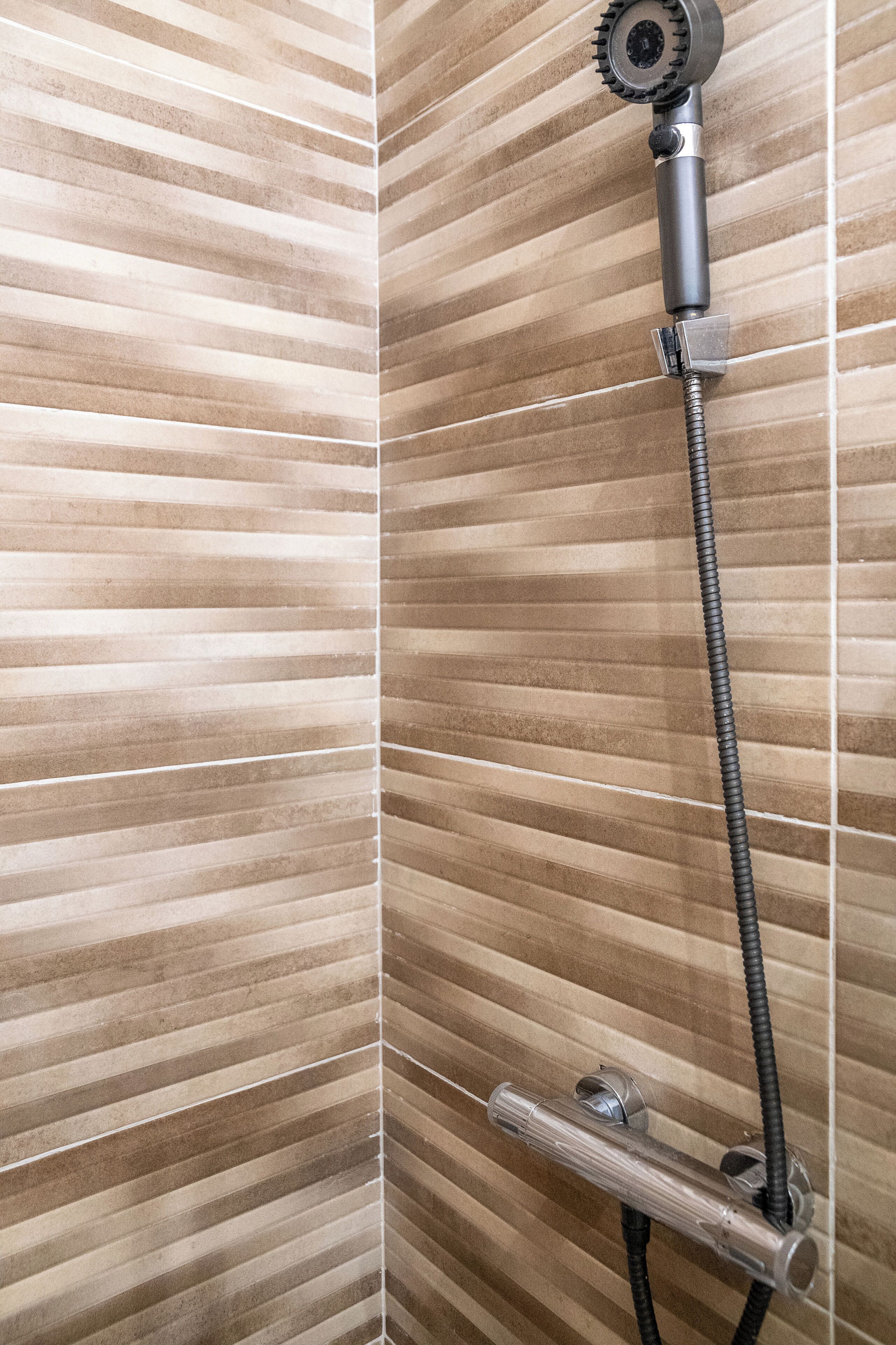 A shower with a handheld showerhead and a flexible hose.