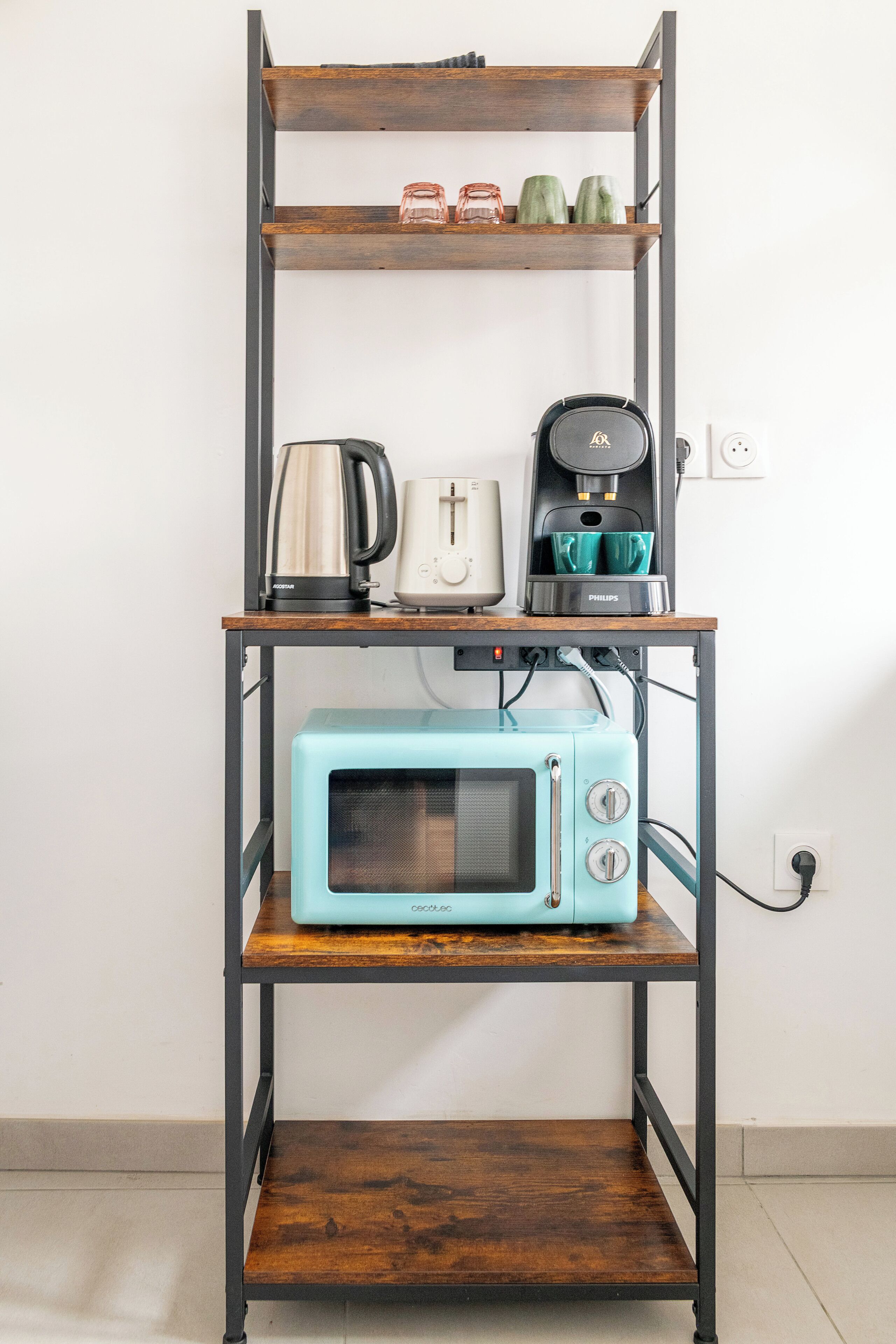 Ein Küchenregal mit Mikrowelle, Kaffeemaschine und Wasserkocher.