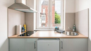 Una cucina compatta con lavastoviglie integrata, lavello in acciaio inossidabile e finestra vista su un edificio in mattoni.
