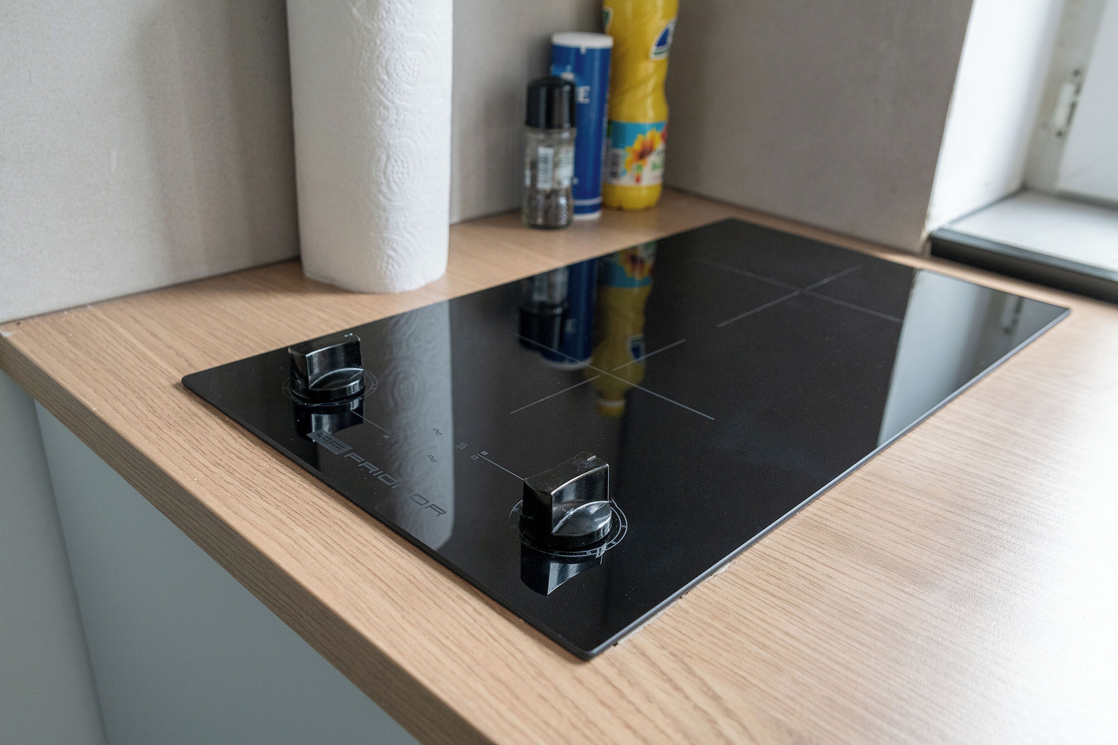 A kitchen with a black induction cooktop and wooden countertop.