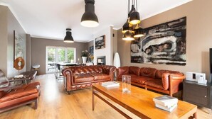A spacious living room with leather sofas, a wooden coffee table, and pendant lighting. - Elegant One-Bedroom House• Terrace & Garage (Lisboa)