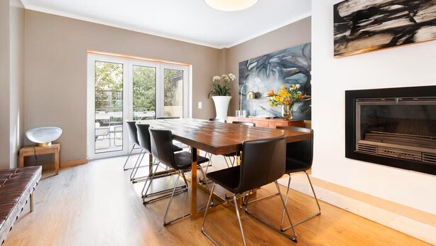 A modern dining area with a wooden table, black chairs, and a pendant light. - Elegant One-Bedroom House• Terrace & Garage (Lisboa)