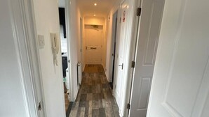 A narrow hallway with white doors on both sides, a tiled floor, and a light fixture on the ceiling. - Apartment - Sleeps4 - Glasgowairport 10 Mins Drive (Renfrew)