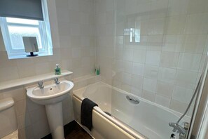 Een aparte badkuip en douche, een diep bad, een haardroger, handdoeken