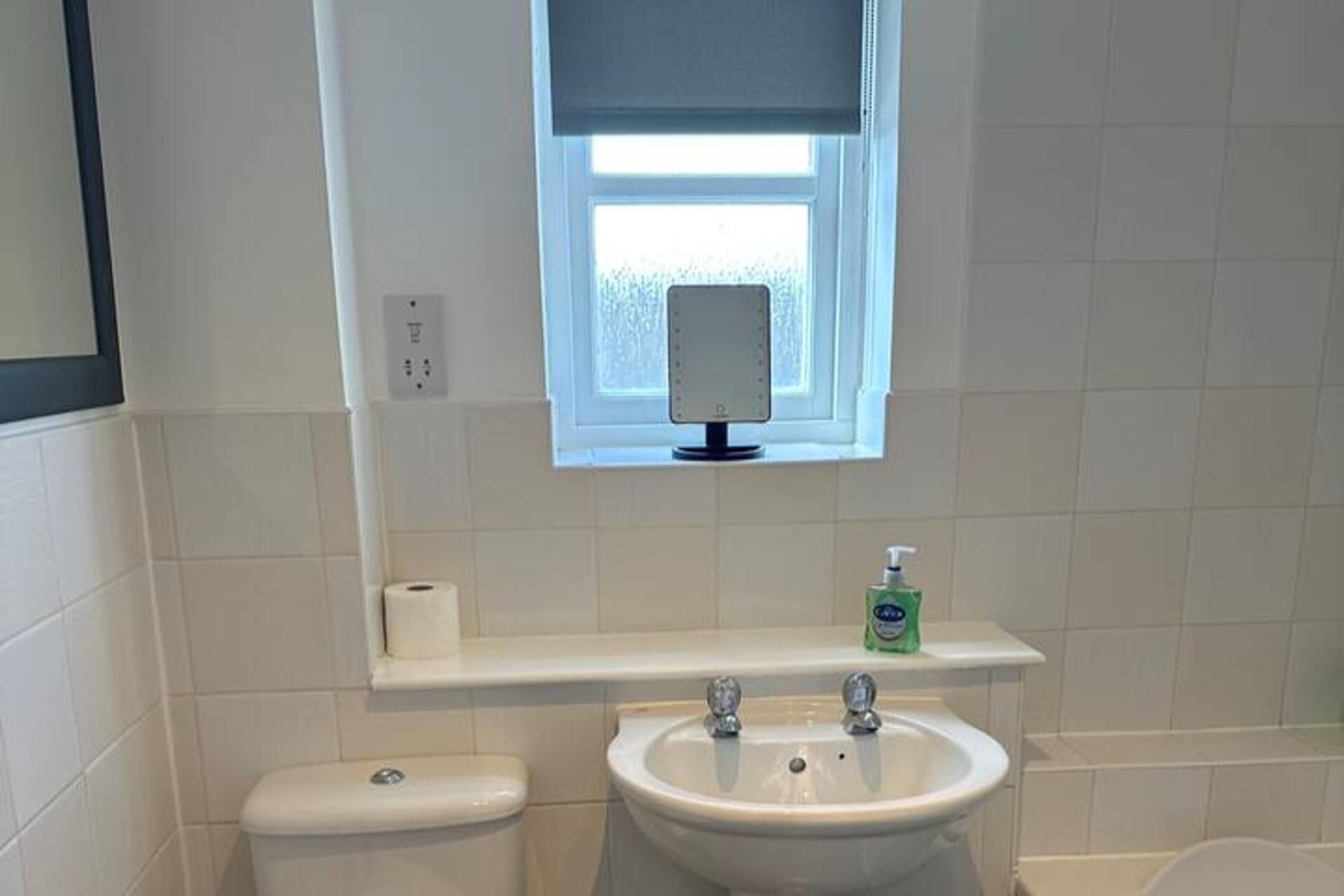 Un baño con inodoro, lavamanos, espejo y ventana.