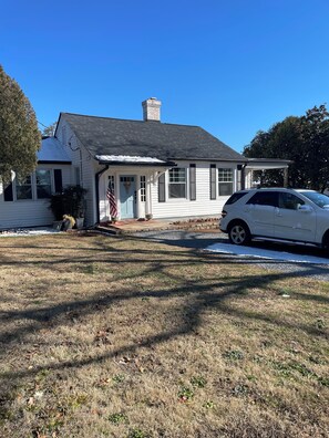 A single-story house with a covered porch, a chimney, and a driveway with a parked car. - Masters week only. Beautiful home within walking distance to Masters Golf. (Augusta)