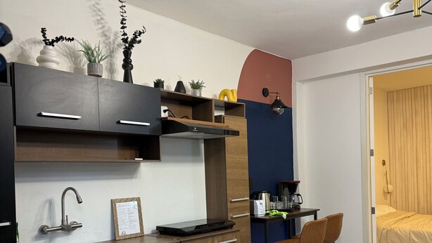 Cuina compacta amb disseny modern, que inclou una placa de cocció integrada, un rentaplat i una petita zona de menjador amb dues cadires.
