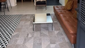 Un saló modern amb un sofà, una taula de centre, una cadira i una catifes amb un disseny original.