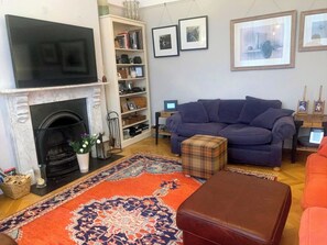 A living room with a fireplace, a sofa, a coffee table, and a bookshelf. - Perfect 3-bedroom Edwardian town house in Bath for a home from home getaway (Bath)