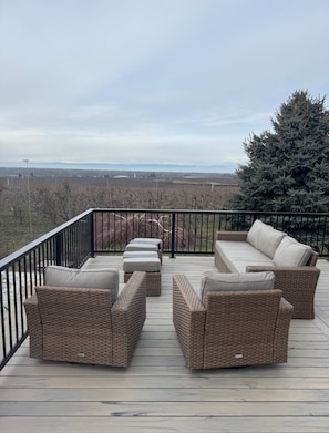 Eine Terrasse mit Korbmöbeln und Blick auf eine weite Landschaft.