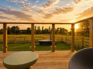 Eine Holzterrasse mit Blick auf ein Wiesenfeld und einem Whirlpool.