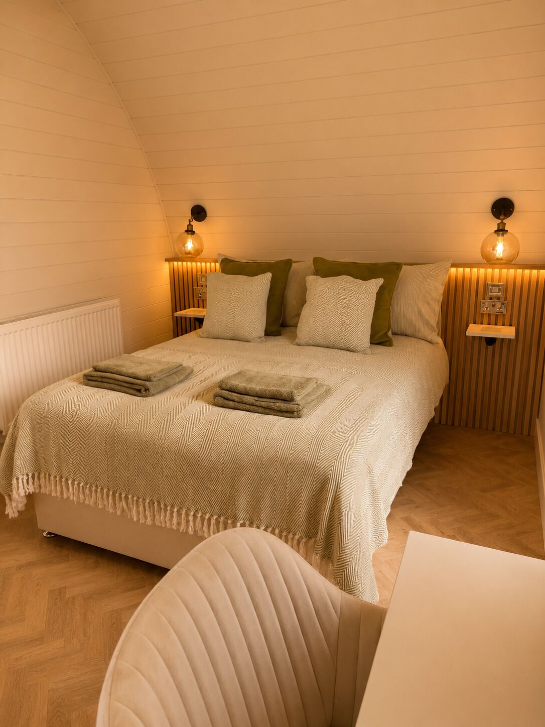 A cozy bedroom with a bed, pillows, a bedside table, and wall-mounted lamps.