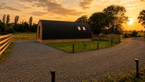 Un petit bâtiment moderne, doté d’un toit incurvé, entouré d’un chemin de gravier et d’une clôture en bois.