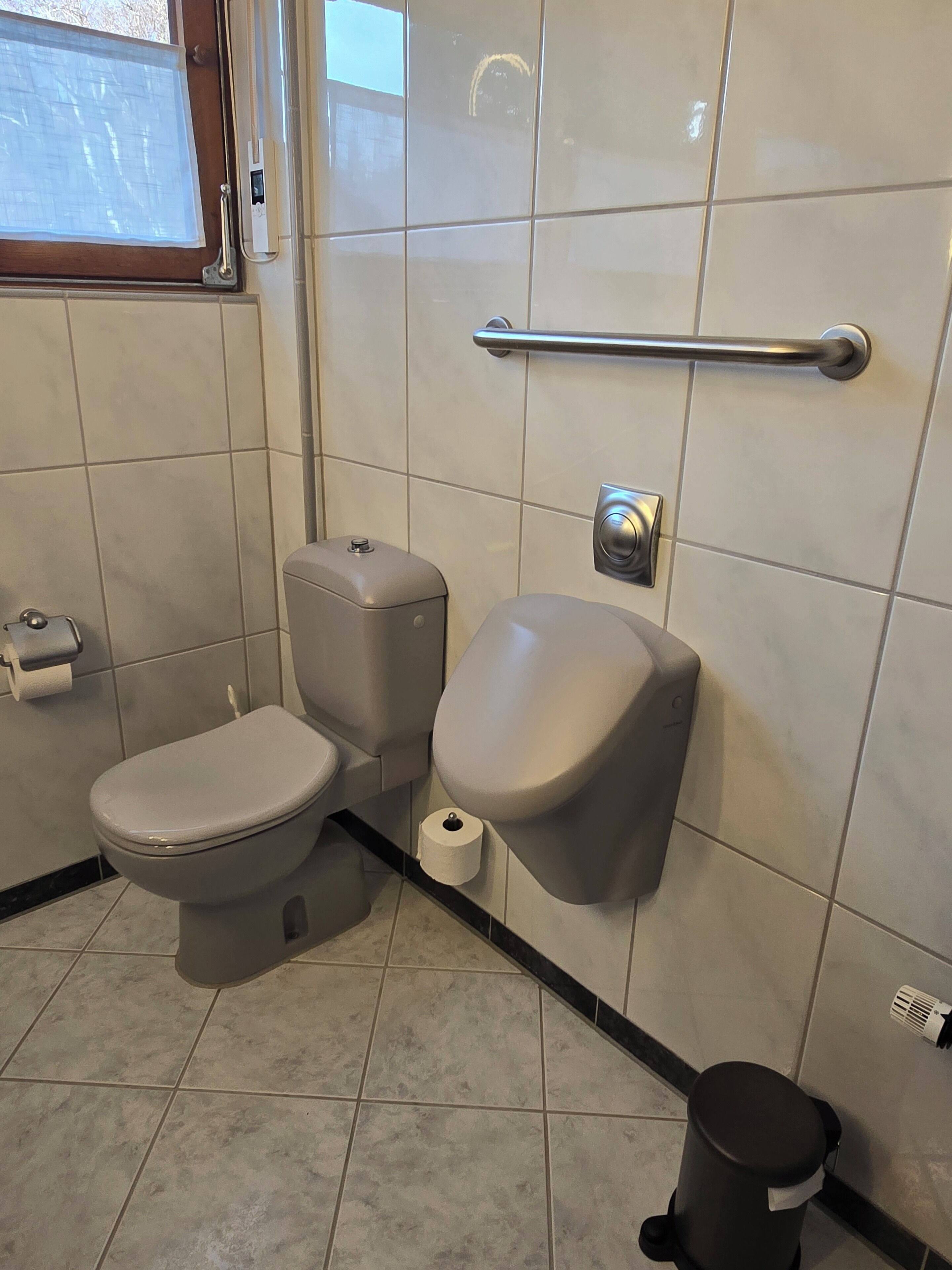 A modern bathroom with a toilet, bidet, and hand dryer.
