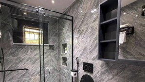 Une salle de bain moderne avec une douche à parois de verre, un grand miroir et un lavabo blanc.