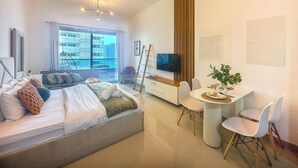 Ein modernes Hotelzimmer mit Bett, Essbereich, Fernseher und Blick auf die Stadt.