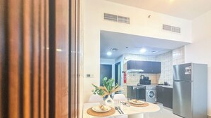 Eine moderne Küche mit Essbereich, inklusive Tisch mit Stühlen, Kühlschrank und Waschmaschine.
