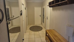 A hallway with a wooden bench, a mirror, a coat rack, and a door at the end. - Großraumbude 44 - House Baltic (Grömitz)