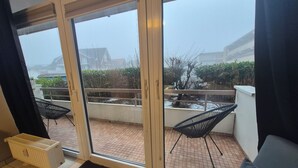 A room with a sliding glass door leading to a balcony with a tiled floor and a small water feature. There are two black chairs on the balcony. - Großraumbude 44 - House Baltic (Grömitz)