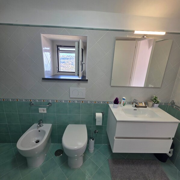Een badkamer met een toilet, wastafel, spiegel en bidet.