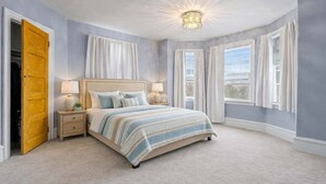 Une chambre à coucher avec un lit, des tables de chevet, une lampe et une fenêtre avec des rideaux.