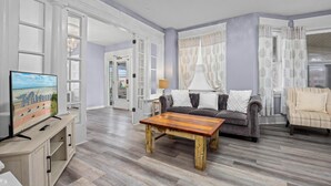 Un salon spacieux avec une table basse en bois, un canapé gris et un fauteuil à rayures.