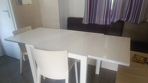 A white dining table with four chairs, a dark sofa, and a striped curtain. - Place of Peace, (Camiers)