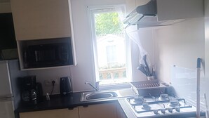 A compact kitchen with a gas stove, a sink, and a microwave. - Place of Peace, (Camiers)