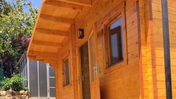 A wooden cabin with a stone foundation, a wooden porch, and a door leading to the interior. - CHALET MARYVONNE LES VANS 07140 (Les Vans)