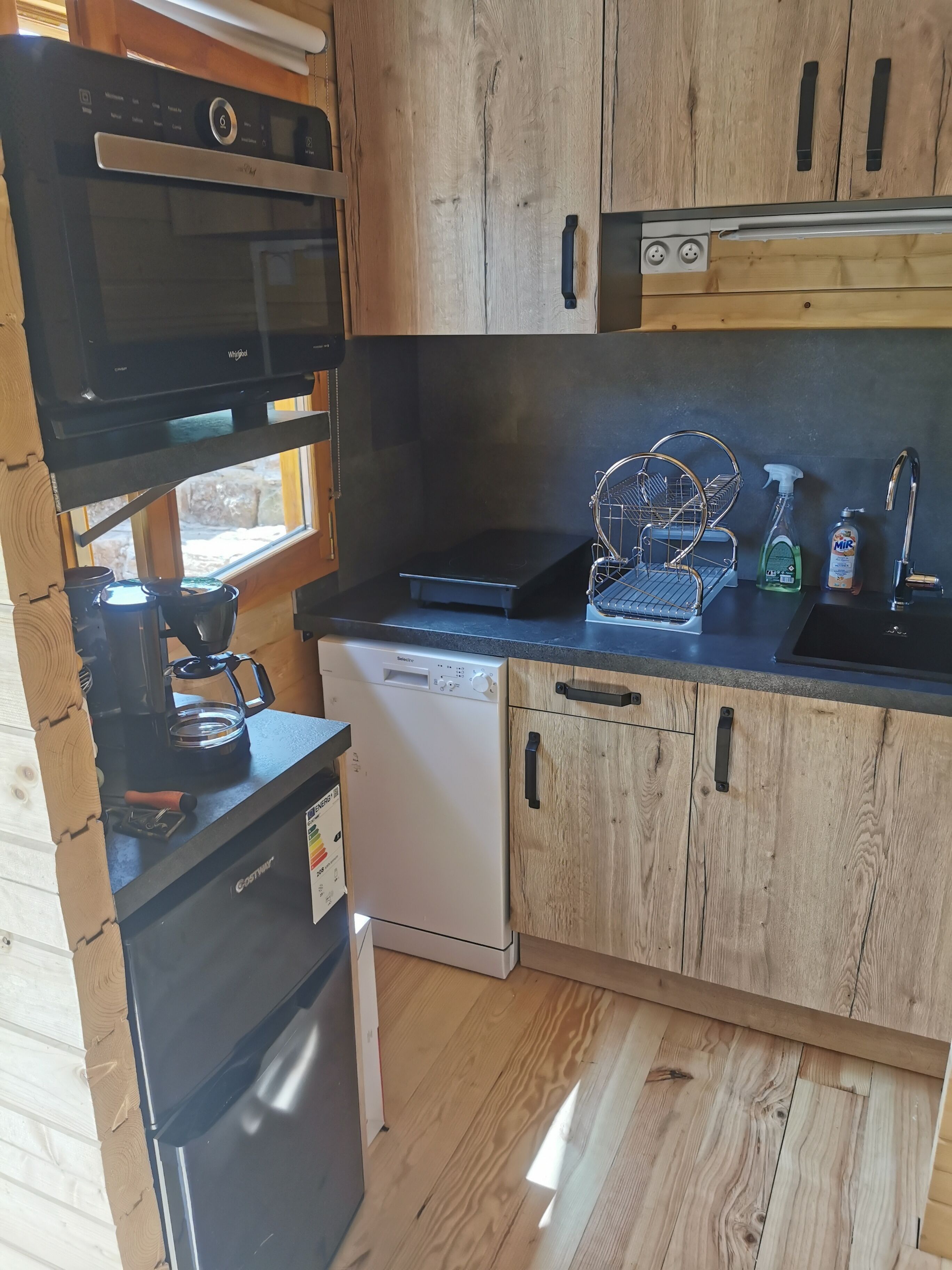 A compact kitchen with a dishwasher, a coffee maker, and a microwave.