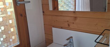 A bathroom with a white sink, a mirror, and a wooden door.