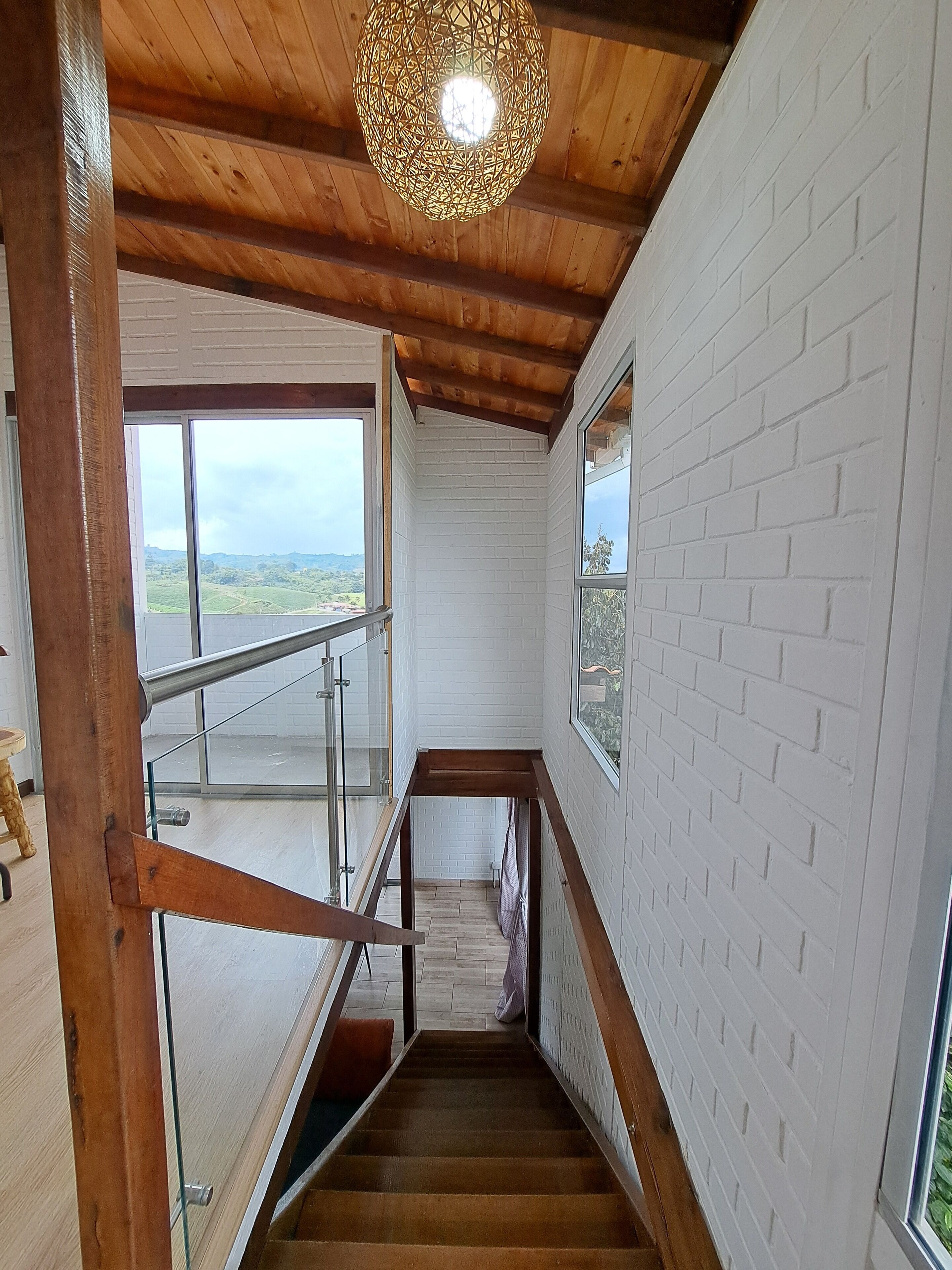 A staircase with wooden railings leading to a balcony with a view of green hills.