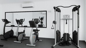 Et moderne fitnesscenter med træningsudstyr, et spejl og en bænk.