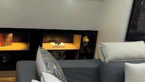 Et moderne soveværelse med en sovesofa, et sengebord med lampe og en hylde med bøger og dekorative genstande.