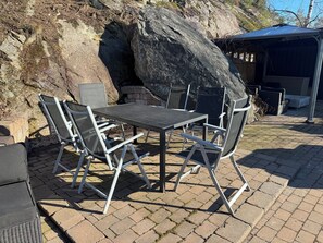 Une terrasse avec une table et des chaises, une formation rocheuse et un espace salon abrité.