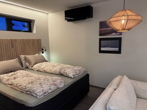 Une chambre à coucher comprenant un lit, un téléviseur, un climatiseur fixé au mur et un luminaire suspendu.