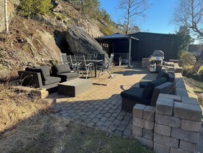 Un espace extérieur aménagé en terrasse, avec des meubles en osier, un barbecue et un coin salon abrité.