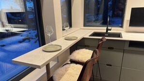 Una cocina moderna con un taburete de bar, una ventana con vistas a un paisaje nevado y un lavabo.