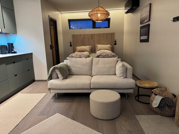 Un salon moderne avec un canapé, un pouf et une petite table ronde.
