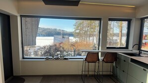 Una cocina moderna con un ventanal amplio, dos taburetes de bar y vistas a un paisaje nevado.