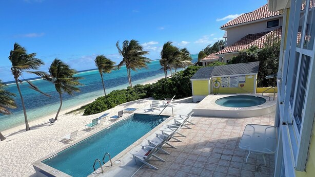 A pool area with two pools, lounge chairs, and a view of the beach and ocean.