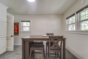 A dining area with a wooden table and four chairs, a small window, and a door. - High Plains Hacienda - 3BR/2BA - Tech Terrace (Lubbock)