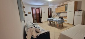 Eine kleine Küche mit Esstisch, Stühlen und einem Kühlschrank.