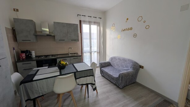 A compact living space with a kitchenette, dining area, and a gray sofa. - La Mola B&B - a stone's throw from Viterbo and Rome (Vignanello)