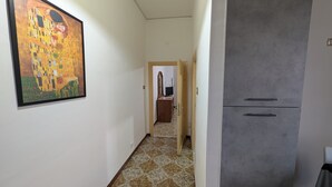 A hallway with a framed painting on the left, a grey cabinet on the right, and a doorway leading to a room with a tiled floor. - La Mola B&B - a stone's throw from Viterbo and Rome (Vignanello)