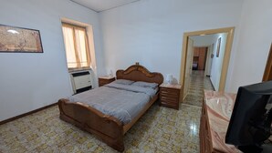 A bedroom with a bed, nightstands, a television, a wardrobe, and a window with curtains. - La Mola B&B - a stone's throw from Viterbo and Rome (Vignanello)