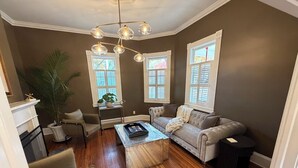 A living room with a sofa, armchairs, a coffee table, and a plant. - Charming & Spacious Historic Charlotte Home- in the heart of the city (Charlotte)